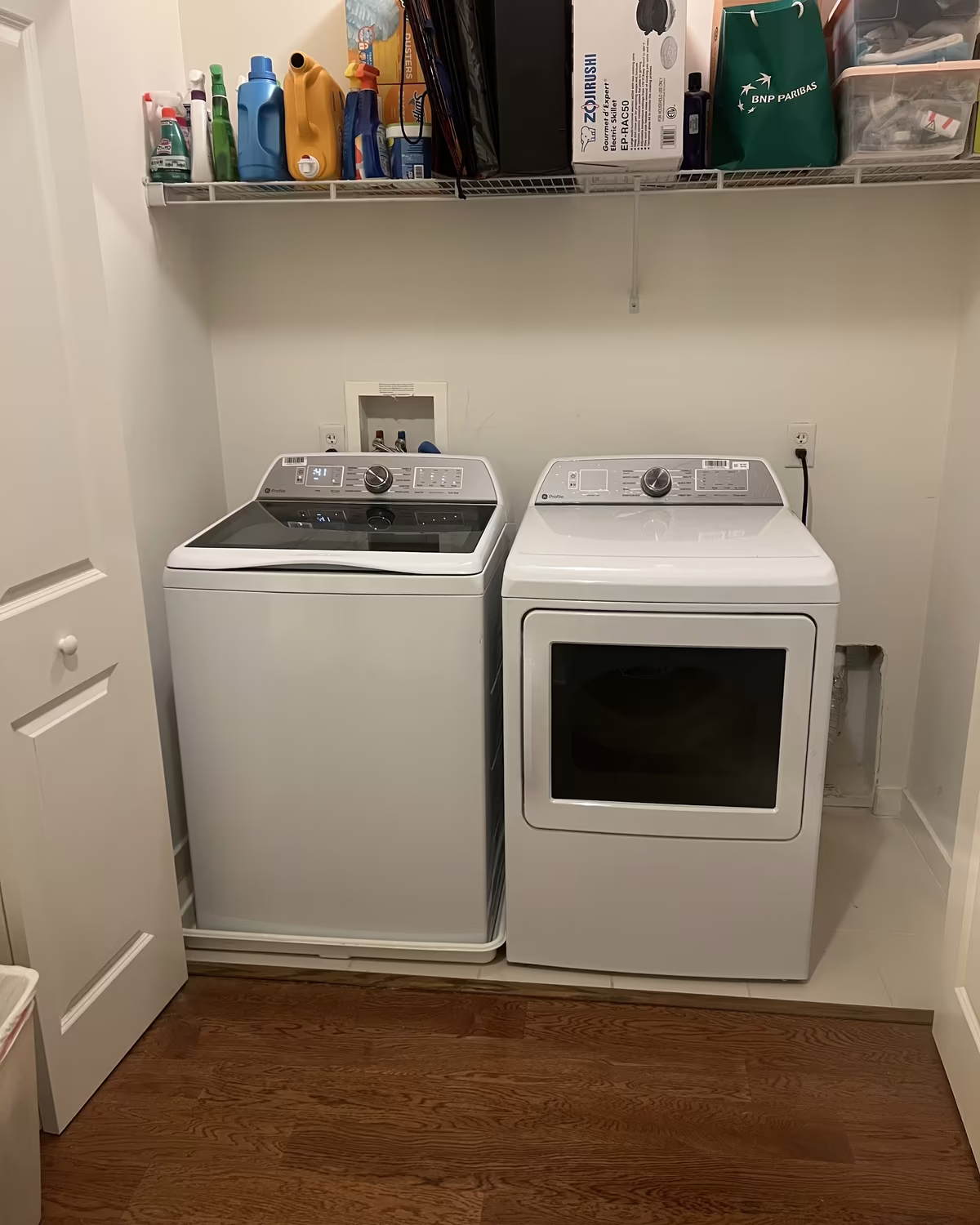 A white top-load washer and dryer installed in a laundry closet