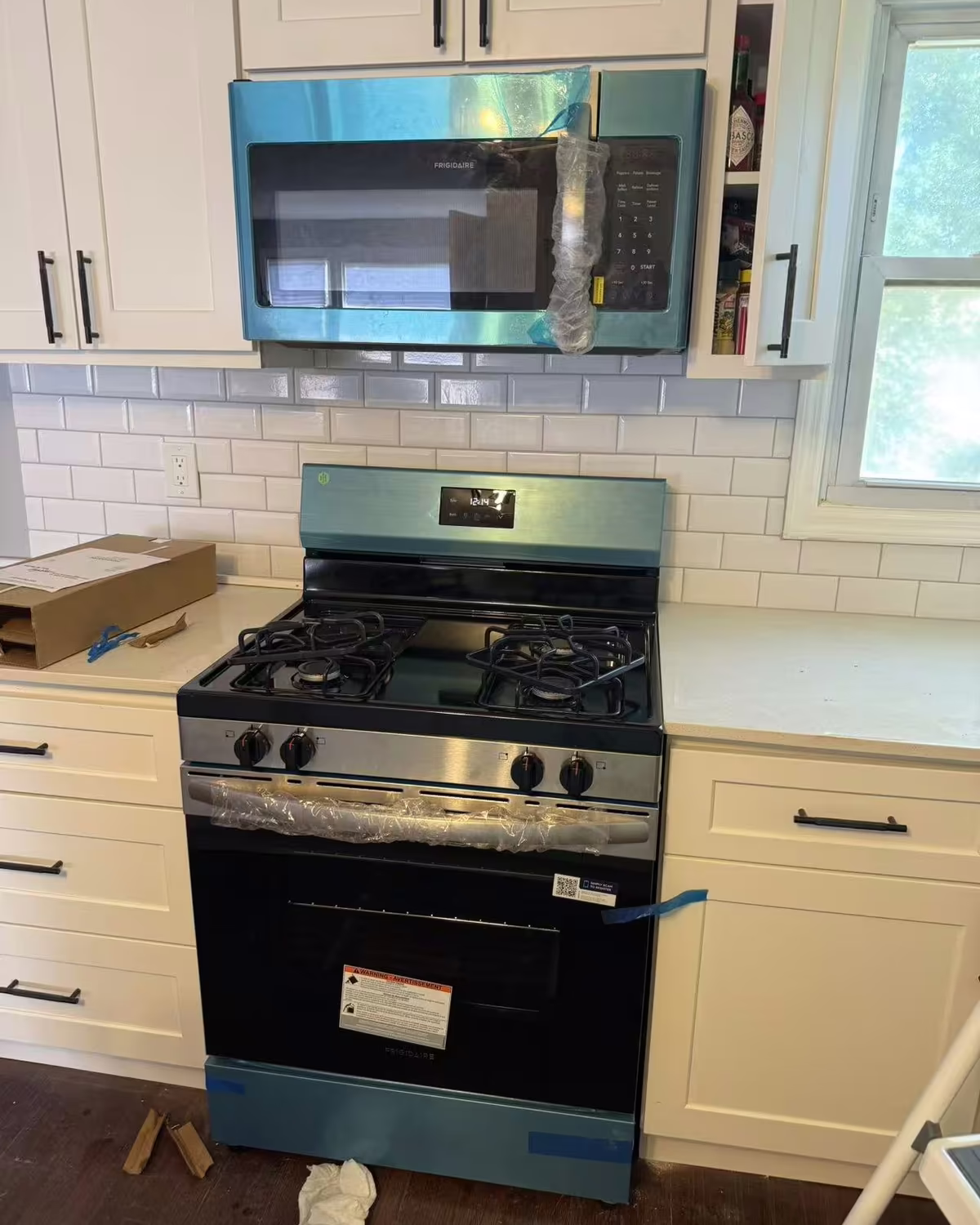 A gas range and over-the-range microwave installed in a white kitchen